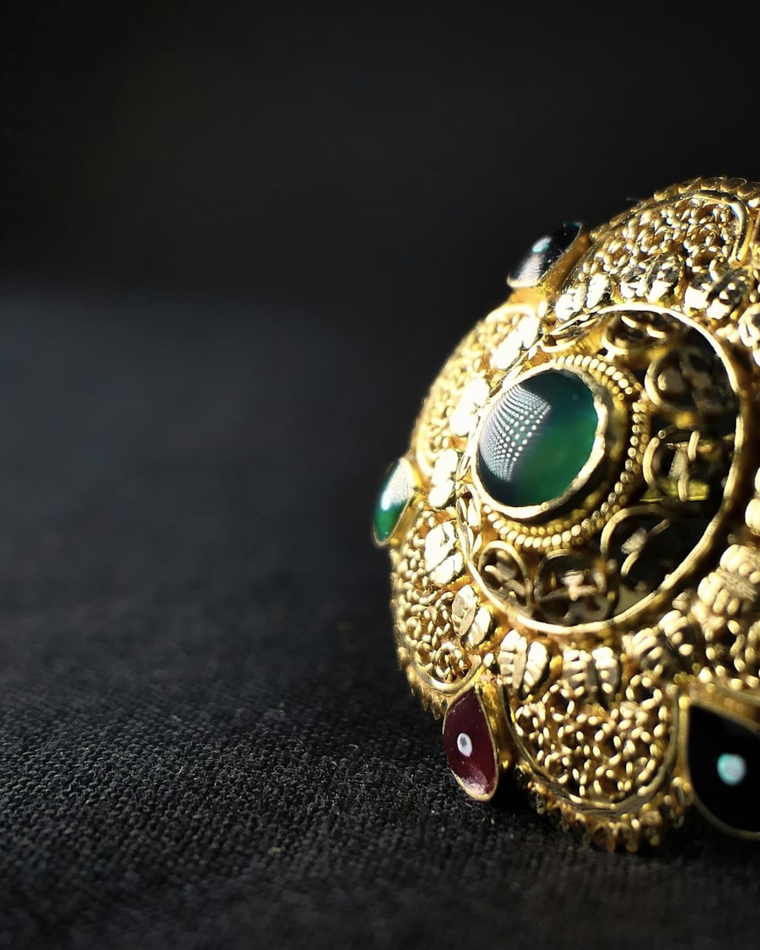 Ornate gold ring set with green and red stones